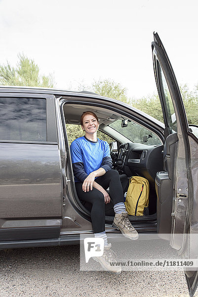 Porträt einer kaukasischen Frau  die bei geöffneter Tür im Auto sitzt
