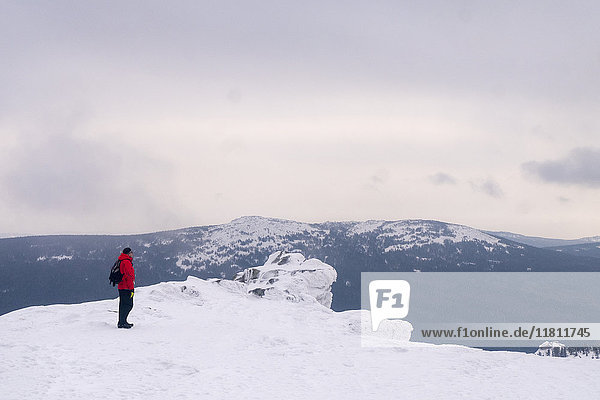Kaukasischer Mann steht auf einem abgelegenen Berg im Winter