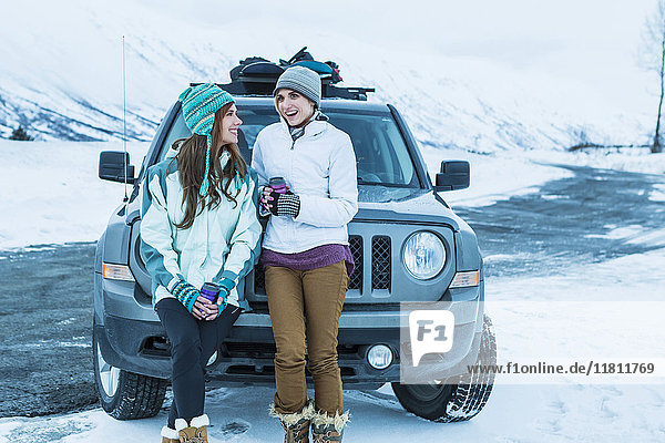 Kaukasische Frauen lachen in der Nähe von Auto im Winter