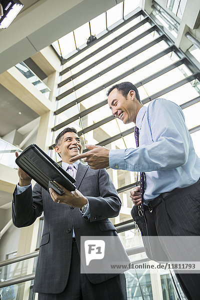 Smiling businessmen using digital tablet in lobby