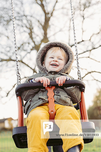 Caucasian boy smiling on swing