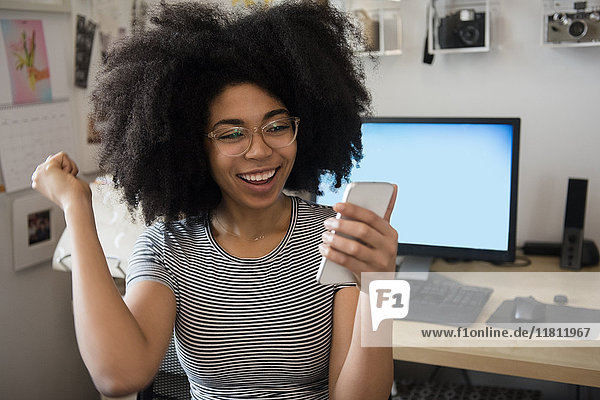 Afroamerikanische Frau  die mit ihrem Handy SMS schreibt und feiert
