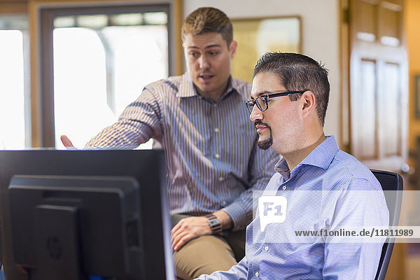 Businessmen talking near computer in office