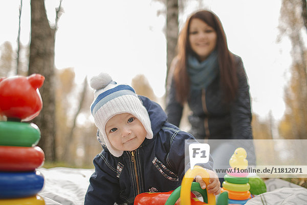 Mutter aus dem Nahen Osten beobachtet ihren kleinen Sohn beim Spielen mit Spielzeug im Park