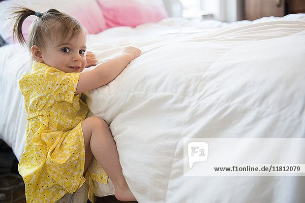 Kaukasisches Babymädchen klettert auf Bett