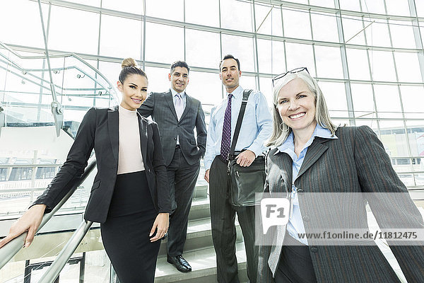 Portrait of smiling business people standing on staircase