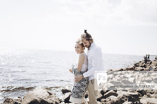 Nahöstliches Paar umarmt sich auf Felsen in der Nähe des Meeres