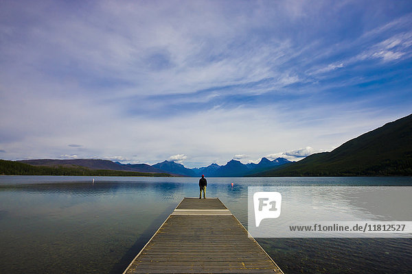 Distant Caucasian man standing on dock at lake