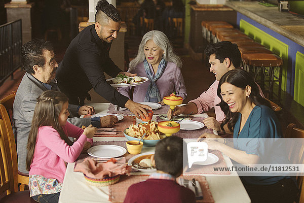 Waiter serving food to family in restaurant