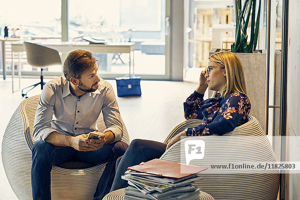 Geschäftsfrau im Gespräch mit einem männlichen Kollegen im Lounge-Bereich