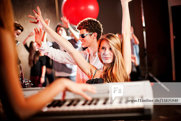 Junge Frau spielt Keyboard mit tanzenden Menschen