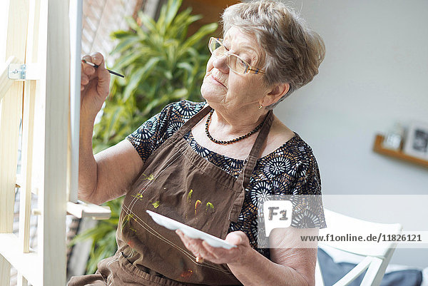 Ältere erwachsene Frau malt auf Staffelei