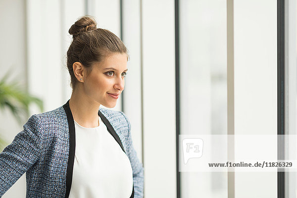 Young confident businesswoman looking through office window