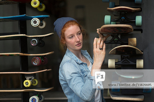 Frau arbeitet im Skateboard-Laden und organisiert Skateboard-Display