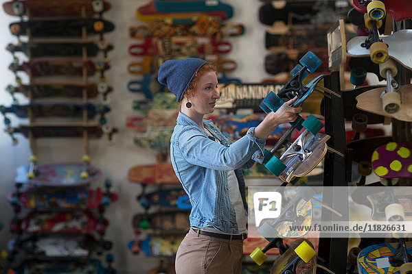 Woman working in skateboard shop  organising skateboard display