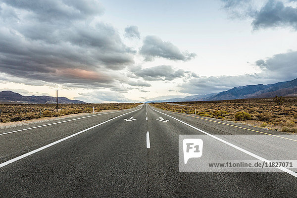 Straight road with direction arrows in Death Valley National Park  California  USA
