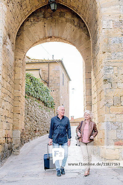 Touristenpaar mit Rollkoffer auf gepflasterter Straße in Siena  Toskana  Italien