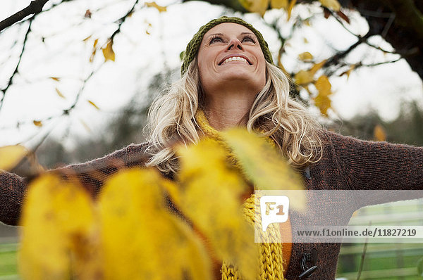 Reife Frau schaut im Herbst lächelnd zum Baum