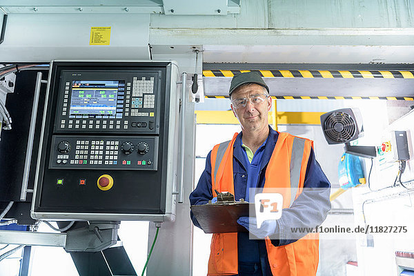 Portrait of engineer with locomotive wheel lathe in train works