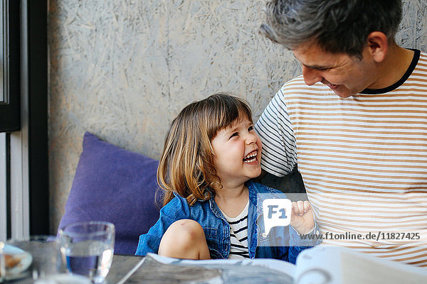 Mädchen lacht mit Vater im Cafe