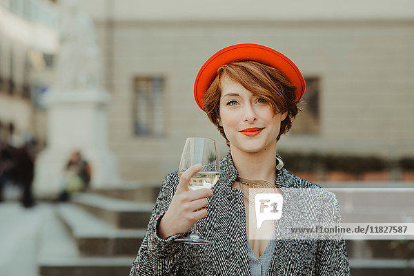 Porträt einer jungen Frau  im Freien  ein Glas Wein haltend