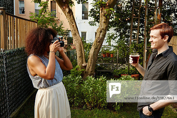 Junge Frau fotografiert Mann im Garten