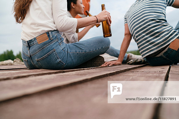 Drei Freunde entspannen sich am Pier  halten Bierflaschen in der Hand  niedriger Abschnitt
