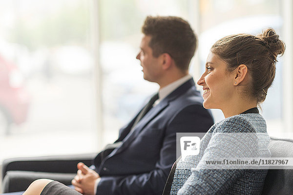 Businessman and woman sitting on sofa in office meeting