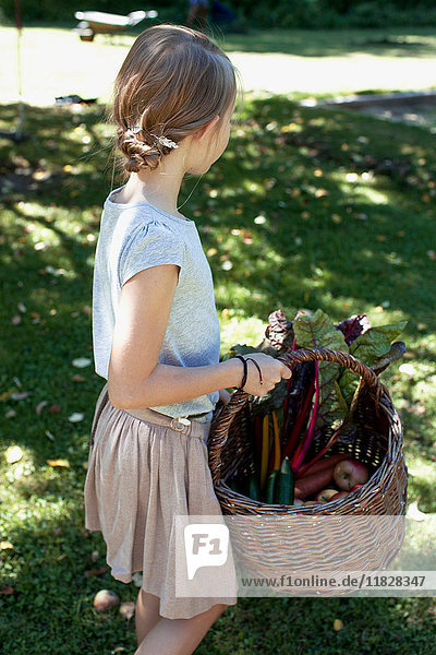 Mädchen trägt einen Korb mit Gemüse