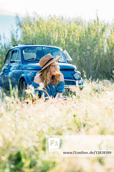 Young woman sitting in tall grass by vintage car  Firenze  Toscana  Italy  Europe