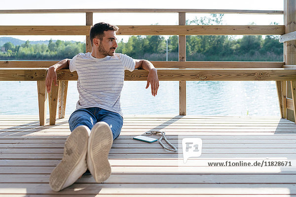 Mann entspannt sich am Pier  Smartphone neben ihm
