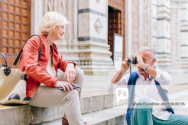 Senior male tourist photographing wife on Siena cathedral stairway  Tuscany  Italy