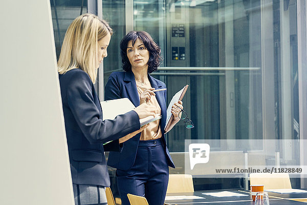 Two businesswomen having discussion in open plan office