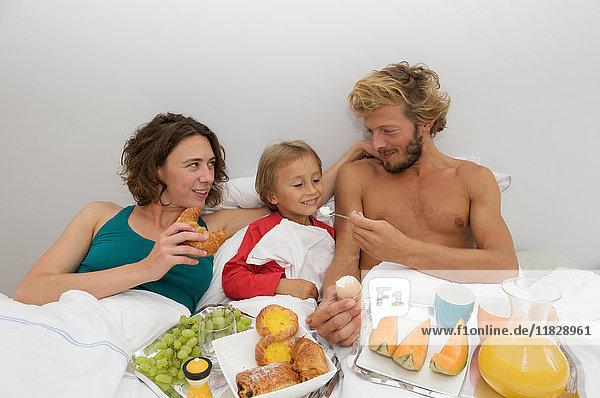 junge Familie beim Frühstück im Bett