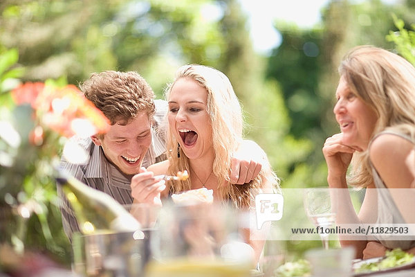 Family laughing at table outdoors