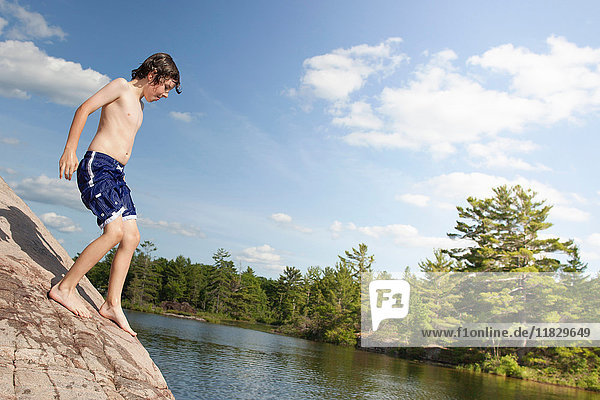 Junge klettert auf Fels am Fluss