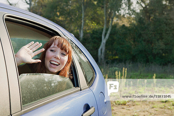 Teenager-Mädchen winkt vom Rücksitz eines Autos