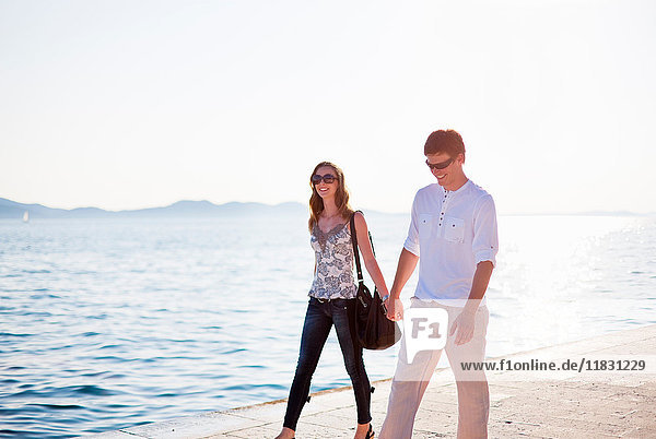 Couple walking hand-in-hand on pier