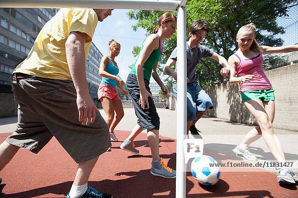 Freunde spielen Fußball auf der Straße in der Stadt