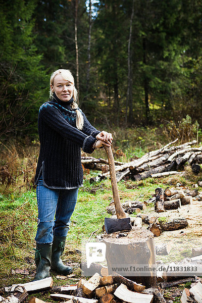 Frau hackt Brennholz im Wald