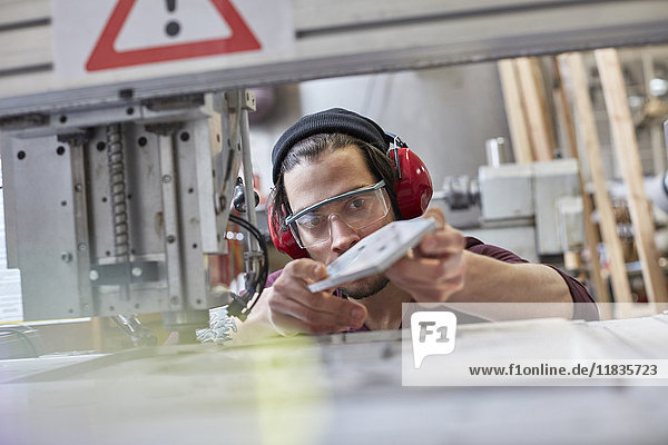 Male designer wearing ear protectors  examining prototype in workshop