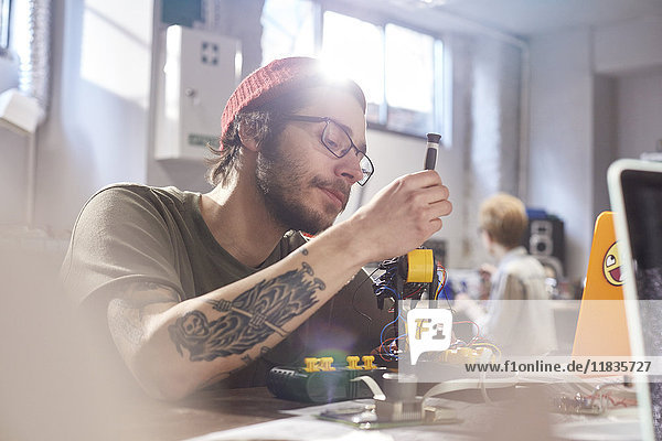 Focused young male designer assembling robotics in workshop