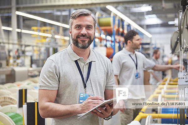 Portrait smiling  confident male supervisor with clipboard in fiber optics factory