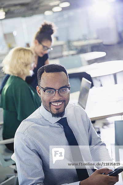 Portrait lächelnder Geschäftsmann SMS mit Handy im Büro