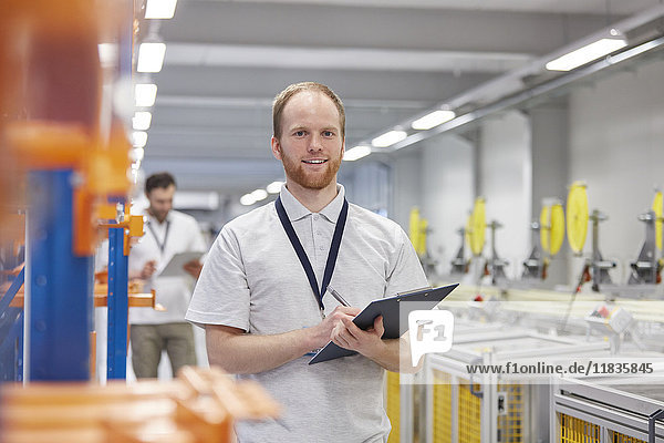 Portrait smiling  confident male supervisor with clipboard in fiber optics factory