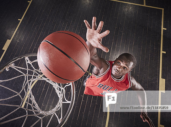 Overhead-Ansicht junger männlicher Basketballspieler  der springt  um den Ball auf die Basketballfelge zu prallen.