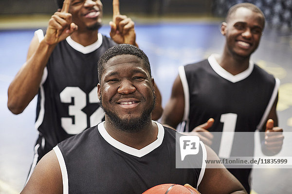 Portrait lächelndes selbstbewusstes junges Basketballer-Team in schwarzen Trikots das den Sieg feiert.