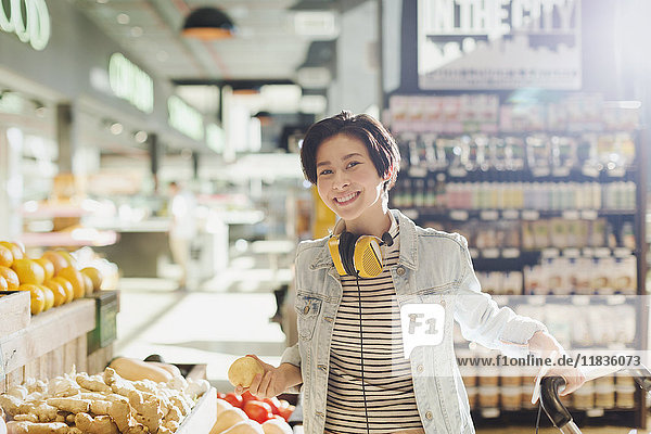 Portrait smiling  confident young woman with headphones grocery shopping in market