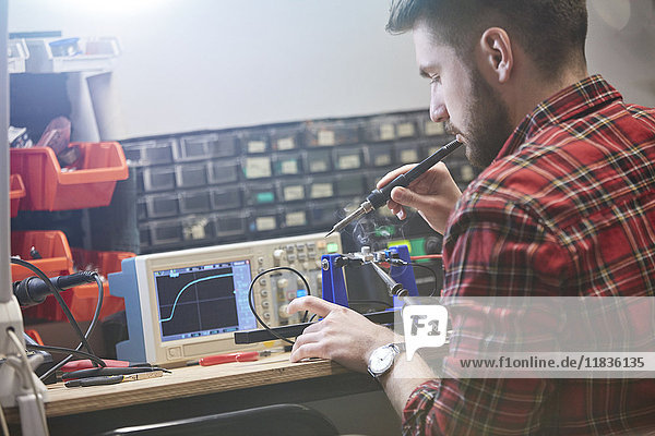 Male engineer assembling electronics  using soldering iron