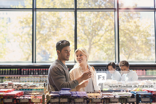 Young couple using cell phone in grocery store market
